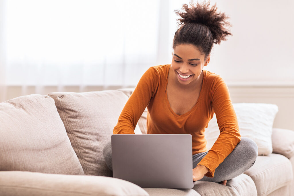 Happy Lady Using Laptop Working From Home Sitting On Sofa