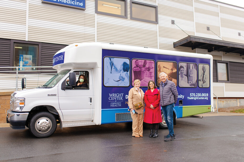 board members standing next to The Wright Center passenger van